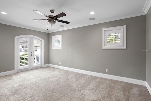 carpeted spare room with ornamental molding, ceiling fan, and french doors