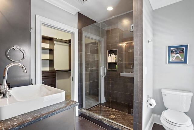 bathroom featuring vanity, a shower with shower door, crown molding, and toilet