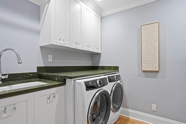 clothes washing area featuring sink, crown molding, light hardwood / wood-style flooring, washer and clothes dryer, and cabinets