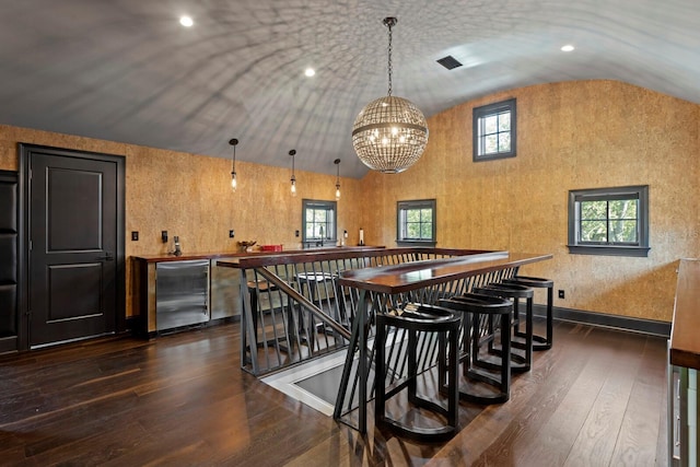 bar featuring decorative light fixtures, lofted ceiling, a chandelier, fridge, and dark wood-type flooring