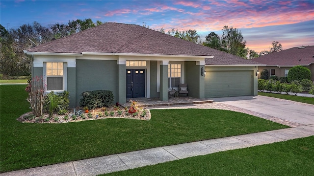 single story home with an attached garage, driveway, roof with shingles, stucco siding, and a front lawn