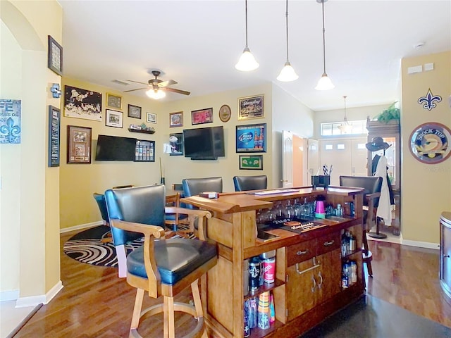 bar with visible vents, hanging light fixtures, a ceiling fan, wood finished floors, and baseboards