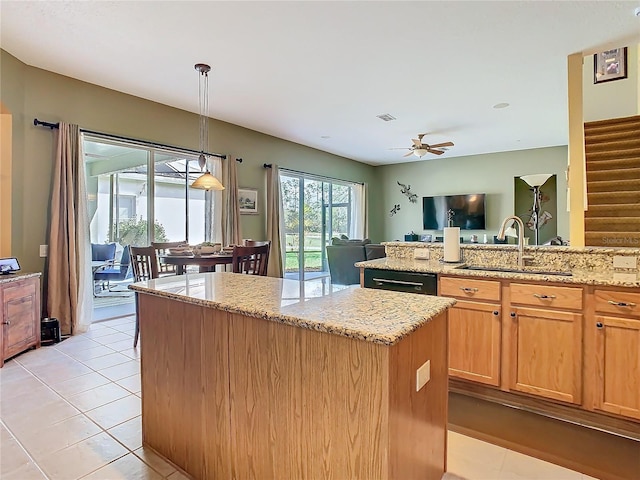 kitchen featuring a kitchen island, light tile patterned flooring, a sink, and light stone counters