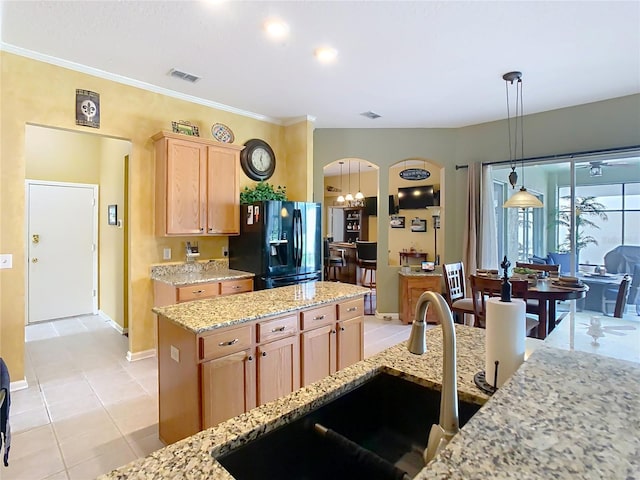 kitchen featuring arched walkways, light tile patterned floors, black fridge with ice dispenser, a sink, and light stone countertops