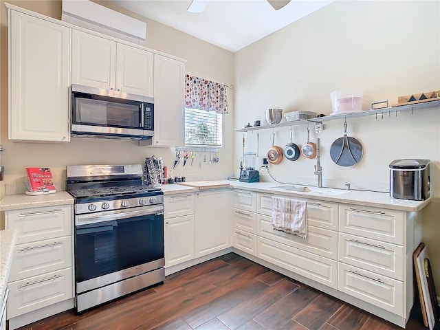 kitchen with appliances with stainless steel finishes, white cabinetry, a sink, and dark wood-style floors