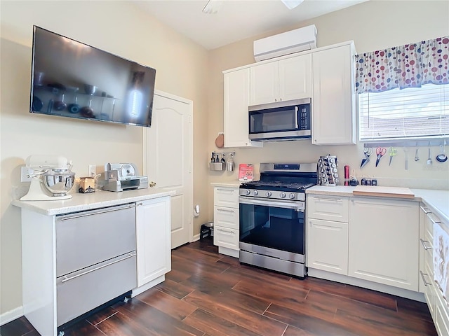 kitchen featuring stainless steel appliances, dark wood-type flooring, white cabinetry, light countertops, and a wall mounted AC