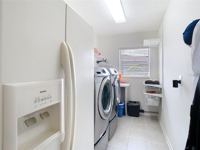 laundry room with laundry area, washer and clothes dryer, light tile patterned flooring, and baseboards