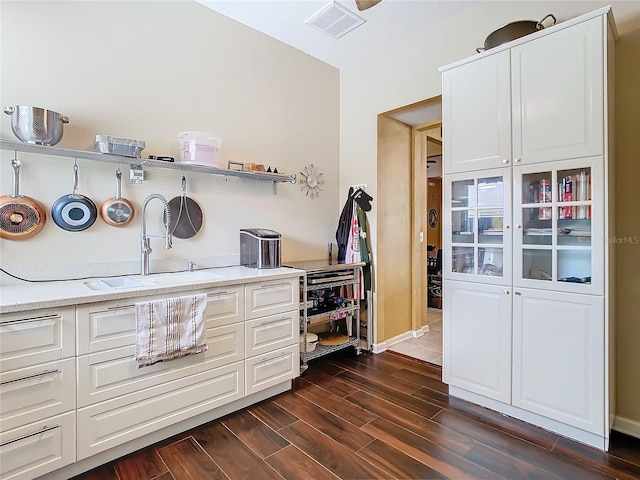25950 Risen Star Dr, Wesley Chapel, FL 33544 - kitchen with baseboards, wood finish floors, white cabinetry, visible vents, and a sink