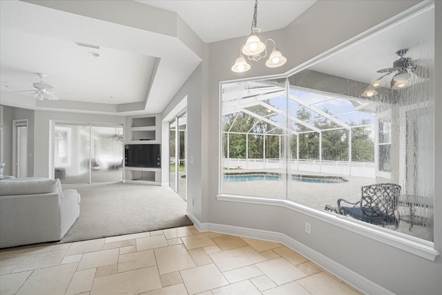 sunroom / solarium with light colored carpet, a raised ceiling, and ceiling fan