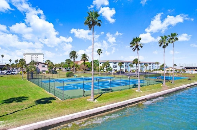 view of tennis court with a yard and a water view