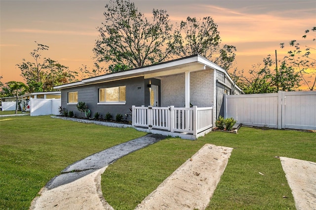 view of front of property with a garage, brick siding, a front lawn, and fence