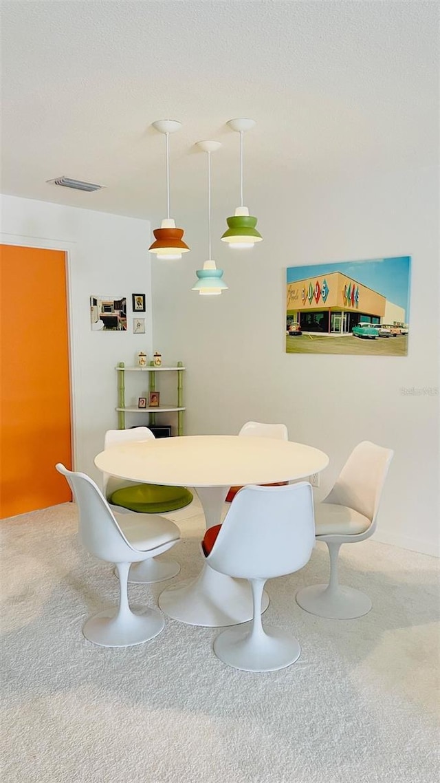 carpeted dining area with a textured ceiling