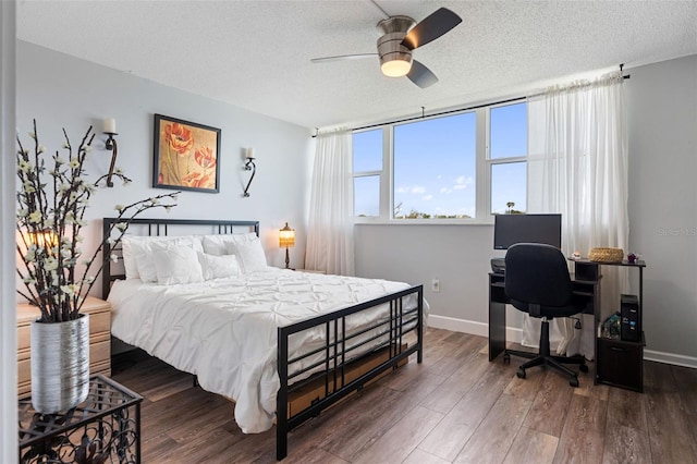 bedroom with a ceiling fan, dark wood finished floors, a textured ceiling, and baseboards