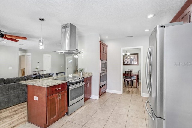 kitchen featuring island range hood, open floor plan, hanging light fixtures, appliances with stainless steel finishes, and light stone countertops