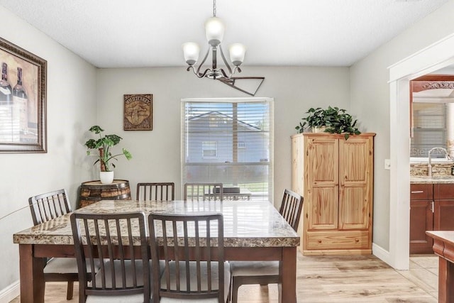 dining area featuring light wood finished floors, baseboards, and an inviting chandelier