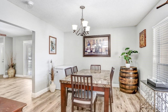 dining area featuring baseboards, light wood-type flooring, and a healthy amount of sunlight