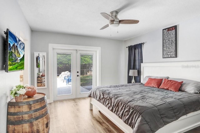 bedroom featuring light wood finished floors, ceiling fan, access to outside, a textured ceiling, and french doors