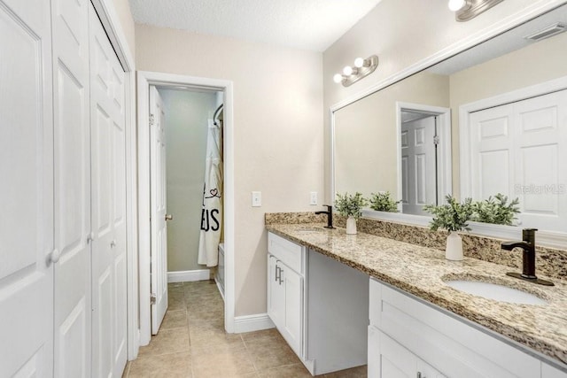 bathroom with double vanity, a closet, visible vents, a sink, and tile patterned floors