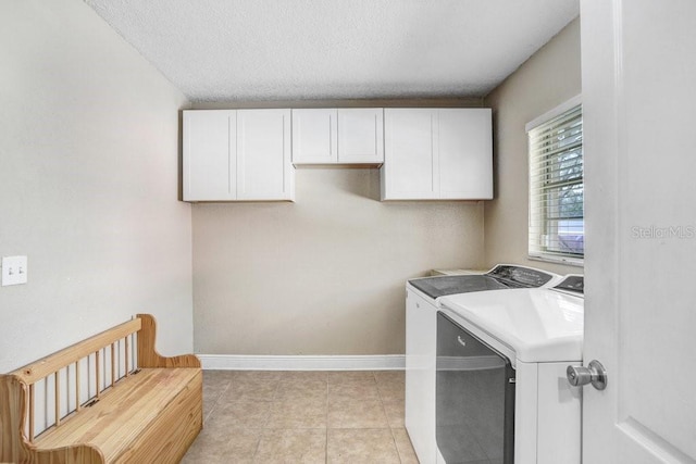 laundry area with light tile patterned floors, cabinet space, a textured ceiling, independent washer and dryer, and baseboards