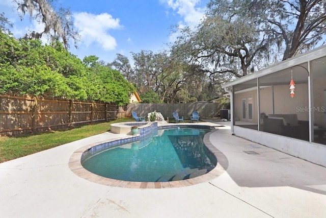 view of pool featuring a sunroom, a fenced backyard, a pool with connected hot tub, and a patio