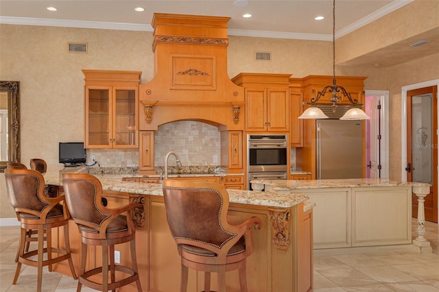 kitchen with light stone counters, stainless steel appliances, a kitchen bar, and hanging light fixtures