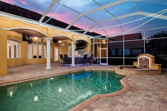 pool at dusk featuring a patio, an outdoor bar, ceiling fan, and glass enclosure