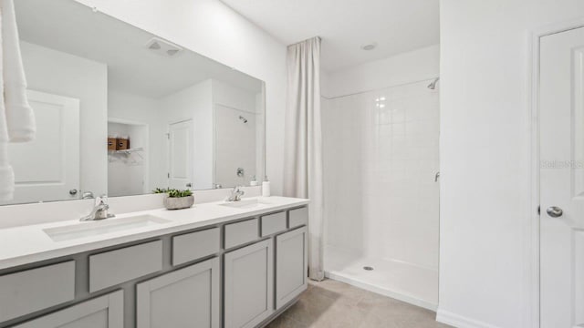 bathroom with tiled shower, vanity, and tile patterned flooring