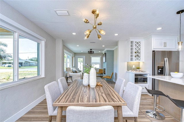 dining space featuring a textured ceiling, an inviting chandelier, and light hardwood / wood-style flooring