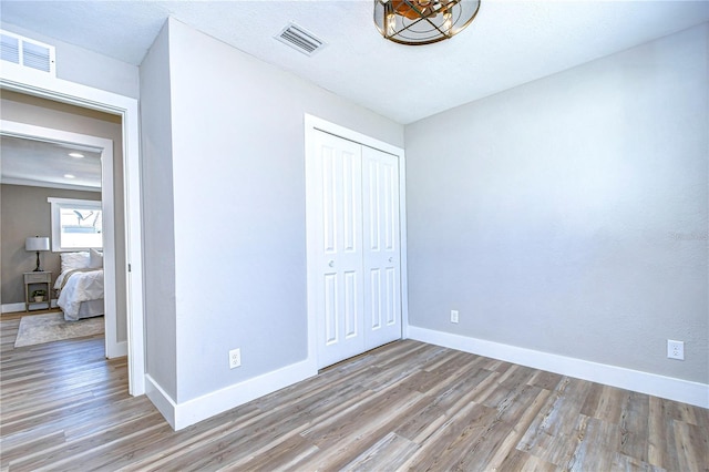 unfurnished bedroom with a textured ceiling, light hardwood / wood-style floors, and a closet