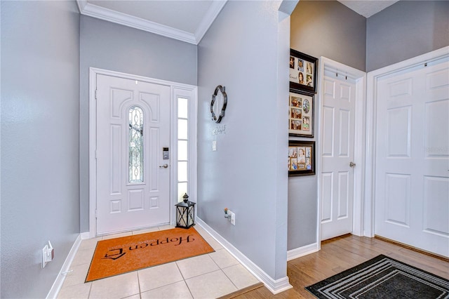 foyer with crown molding and light tile patterned flooring