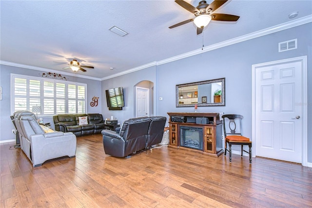 living room with hardwood / wood-style flooring, crown molding, and ceiling fan