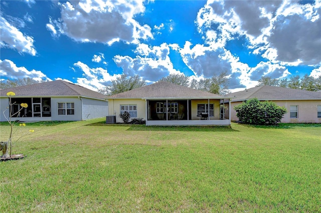 back of property with a sunroom, central AC, and a lawn