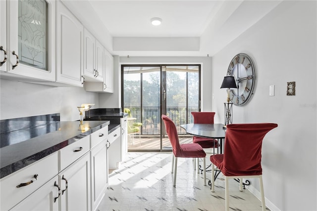 kitchen with dark countertops, baseboards, and white cabinets