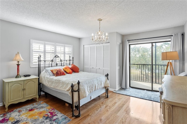 bedroom featuring access to outside, multiple windows, light wood finished floors, and an inviting chandelier