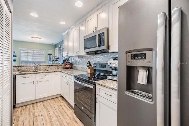 kitchen featuring appliances with stainless steel finishes, sink, white cabinets, and light stone counters