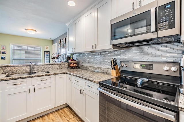 kitchen with white cabinetry, sink, light stone countertops, and appliances with stainless steel finishes