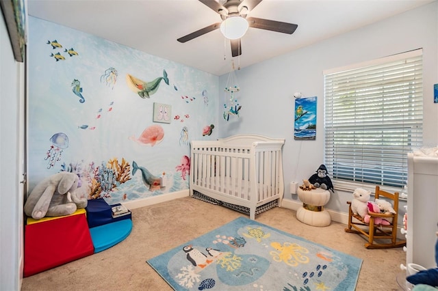 carpeted bedroom with a nursery area and ceiling fan