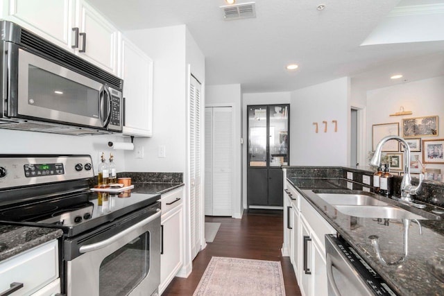 kitchen featuring visible vents, appliances with stainless steel finishes, white cabinets, and a sink