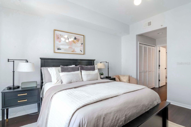 bedroom with baseboards, a closet, visible vents, and wood finished floors