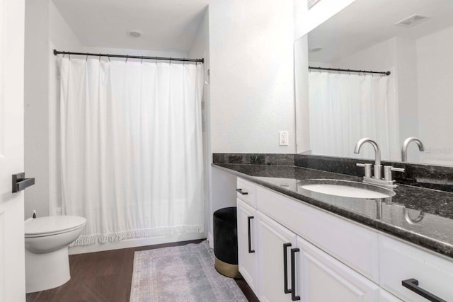 bathroom featuring visible vents, toilet, vanity, wood finished floors, and a shower with curtain