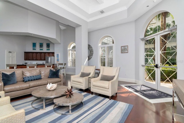 living room featuring baseboards, wood finished floors, a high ceiling, crown molding, and french doors