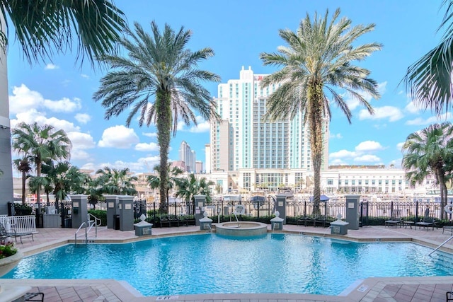 community pool featuring a patio area, fence, and a city view