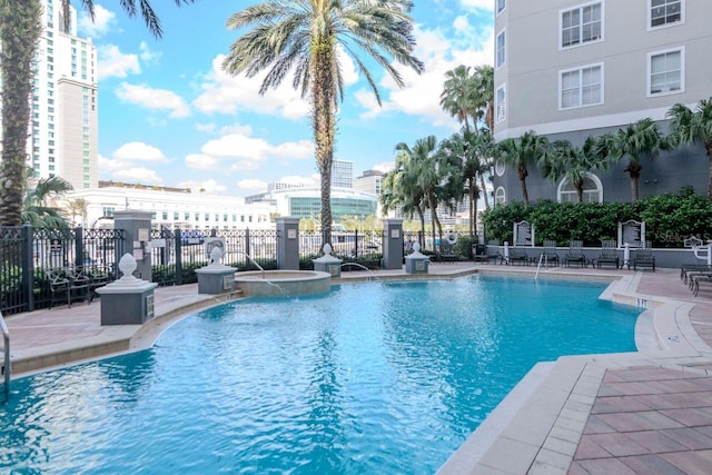 community pool featuring a view of city, a patio area, and fence