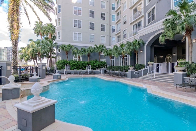 community pool with a patio and fence