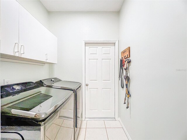 washroom with independent washer and dryer, light tile patterned flooring, and cabinet space