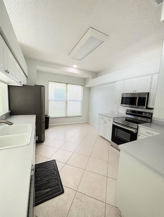 1609 Shady Oaks Dr, Oldsmar, FL 34677 - kitchen featuring stainless steel appliances, white cabinetry, light tile patterned flooring, a sink, and a textured ceiling