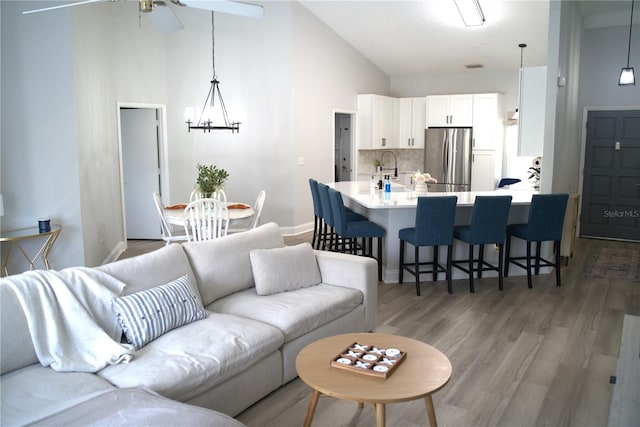 living room featuring dark wood-type flooring, sink, high vaulted ceiling, and a notable chandelier