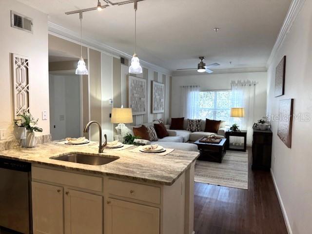 kitchen with sink, crown molding, dishwasher, light stone counters, and kitchen peninsula