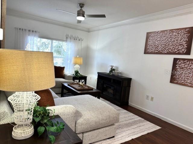 living room with hardwood / wood-style floors, a fireplace, ornamental molding, and ceiling fan