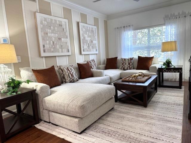 living room featuring hardwood / wood-style floors, ornamental molding, and ceiling fan